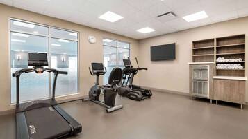 A fitness room with treadmills, a water dispenser, and a TV on the wall.