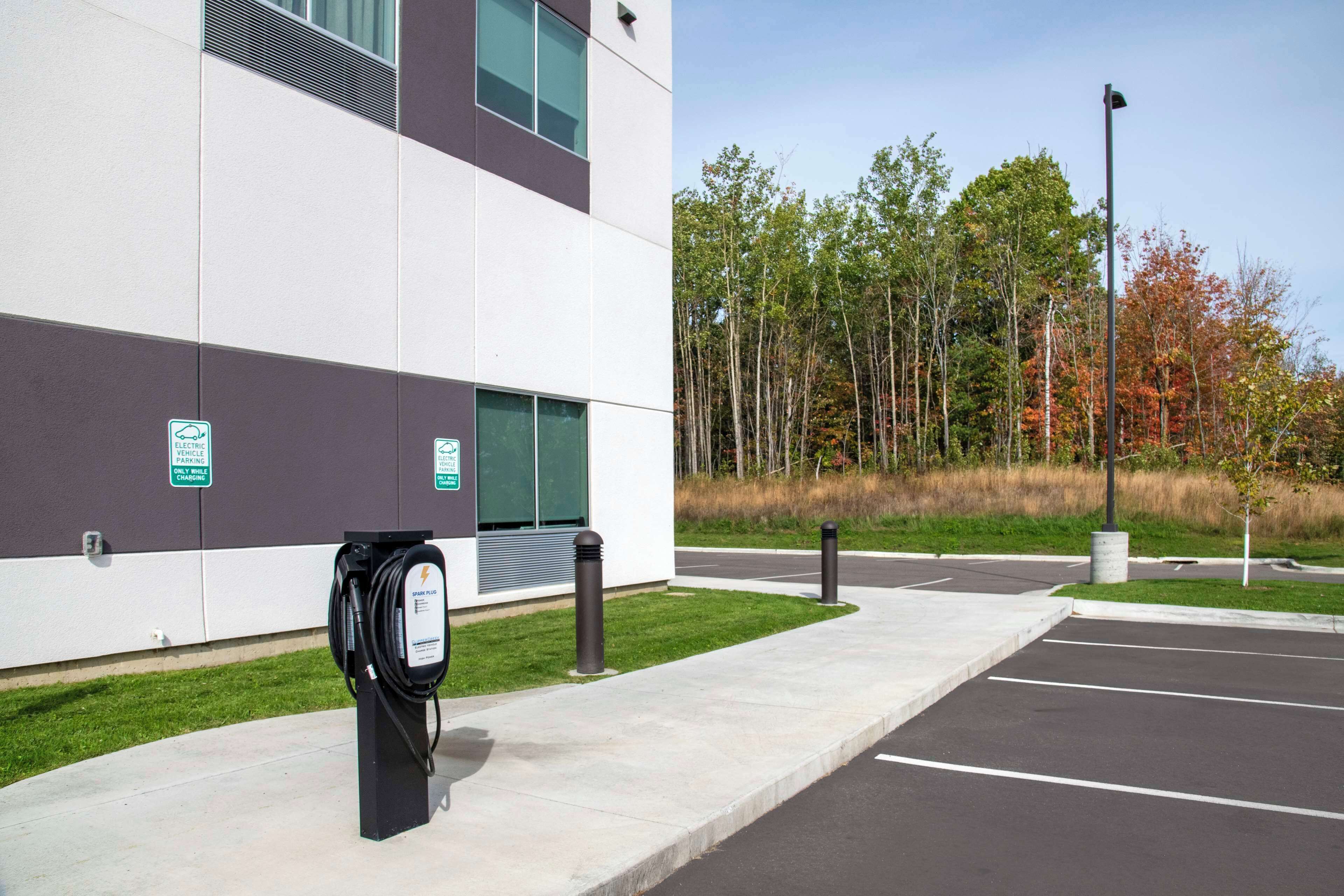A modern building with a parking lot and electric vehicle charging station.