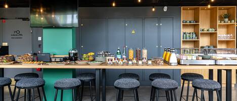 Un área de bar moderna con taburetes, una barra con diversos artículos y una pared de acento verde.