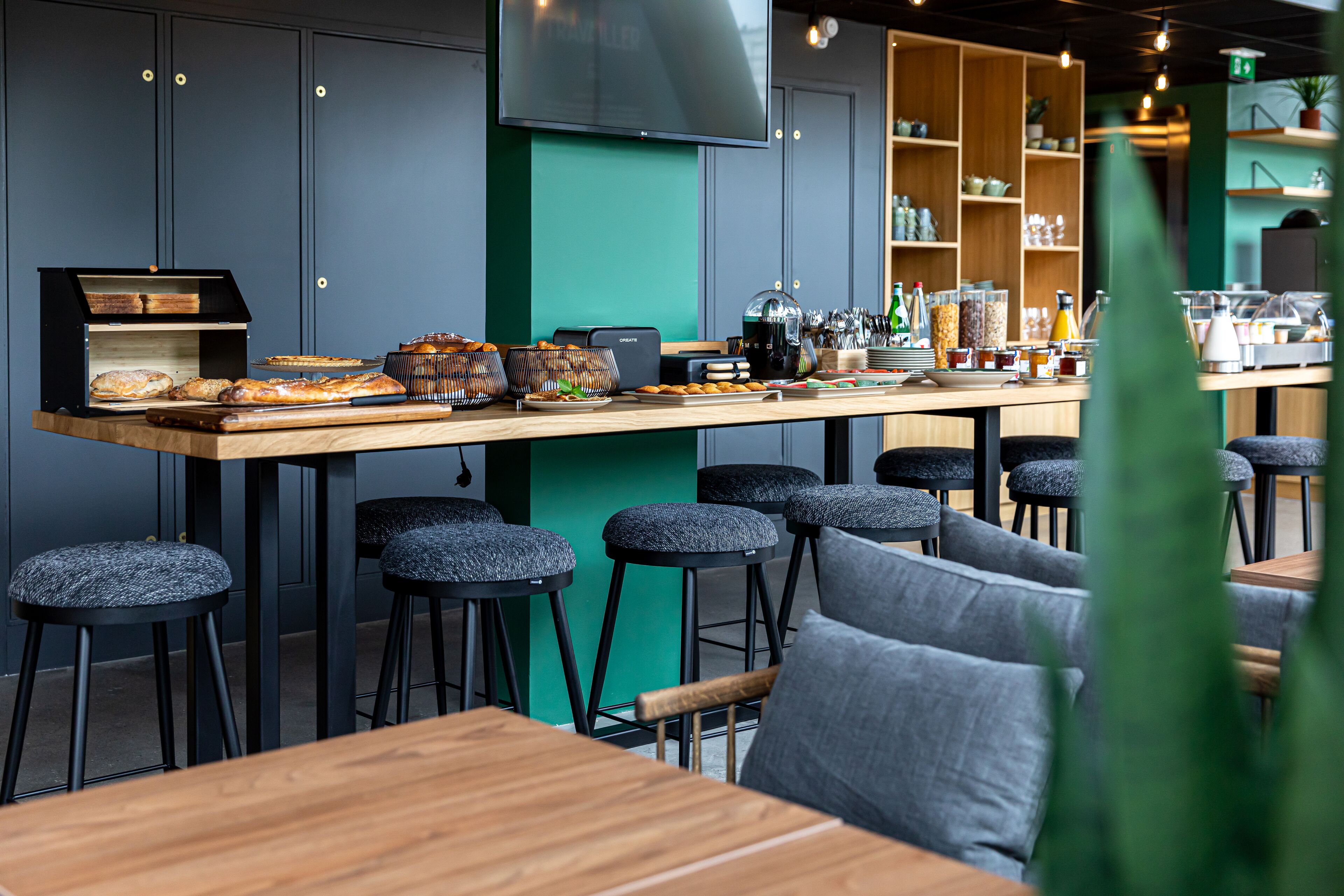 A modern café with a long counter, stools, and a variety of food items displayed.
