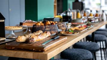 A breakfast buffet with various pastries and bread on a wooden counter.