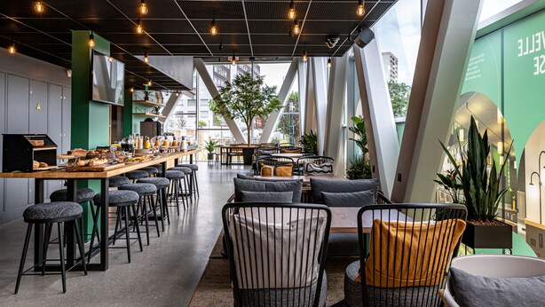 A modern cafe with a long counter, bar stools, and comfortable seating.