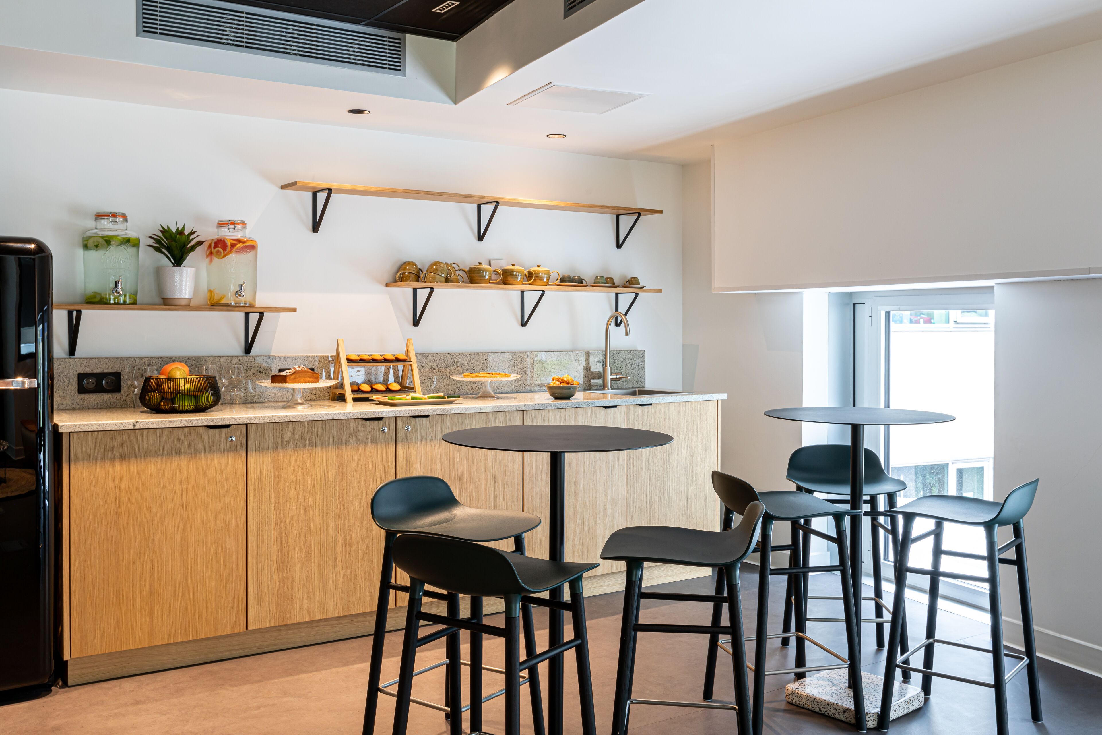 A modern kitchen with wooden cabinets, a central island, and black bar stools.