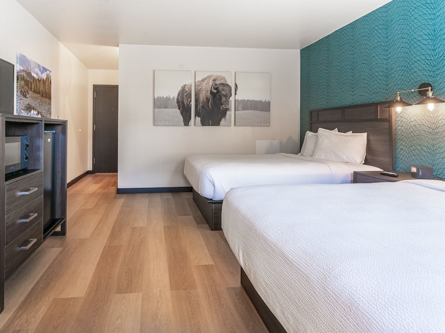 A hotel room with two beds, a TV, a dresser, and artwork on the walls.