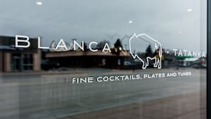 A window with the text "BLANCA" and "TATANKA" along with "FINE COCKTAILS, PLATES AND TUNES" indicating a restaurant or bar. - The Scout INN (Cody)