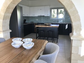 Une cuisine avec une table en bois, des bols en marbre et des tabourets de bar noirs.