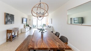 Ein geräumiger Essbereich mit einem langen Holztisch, einer Kandelaber und Blick auf das Wohnzimmer im Hintergrund.