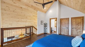 A spacious bedroom with a large bed, wooden ceiling, and a view of the bathroom through an open door. - Modern 3 Bedroom Cabin with Mountain Views! (Sevierville)