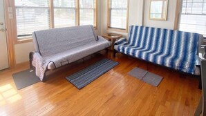 Ein Zimmer mit einer Couch, einem kleinen Tisch und einem Fenster mit Jalousien.