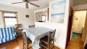 Ein Essbereich mit Tisch, Stühlen, einem Deckenventilator und einem Gemälde an der Wand.