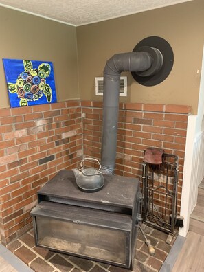 Cozy room with a stove and brick wall, featuring a metal rack and abstract art.