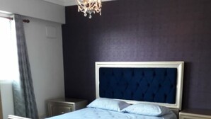 Een slaapkamer met een groot bed, een kroonluchter en een nachtkastje.