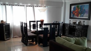 Een moderne woonkamer met een eethoek, een bank, een open haard en een schilderij aan de muur.