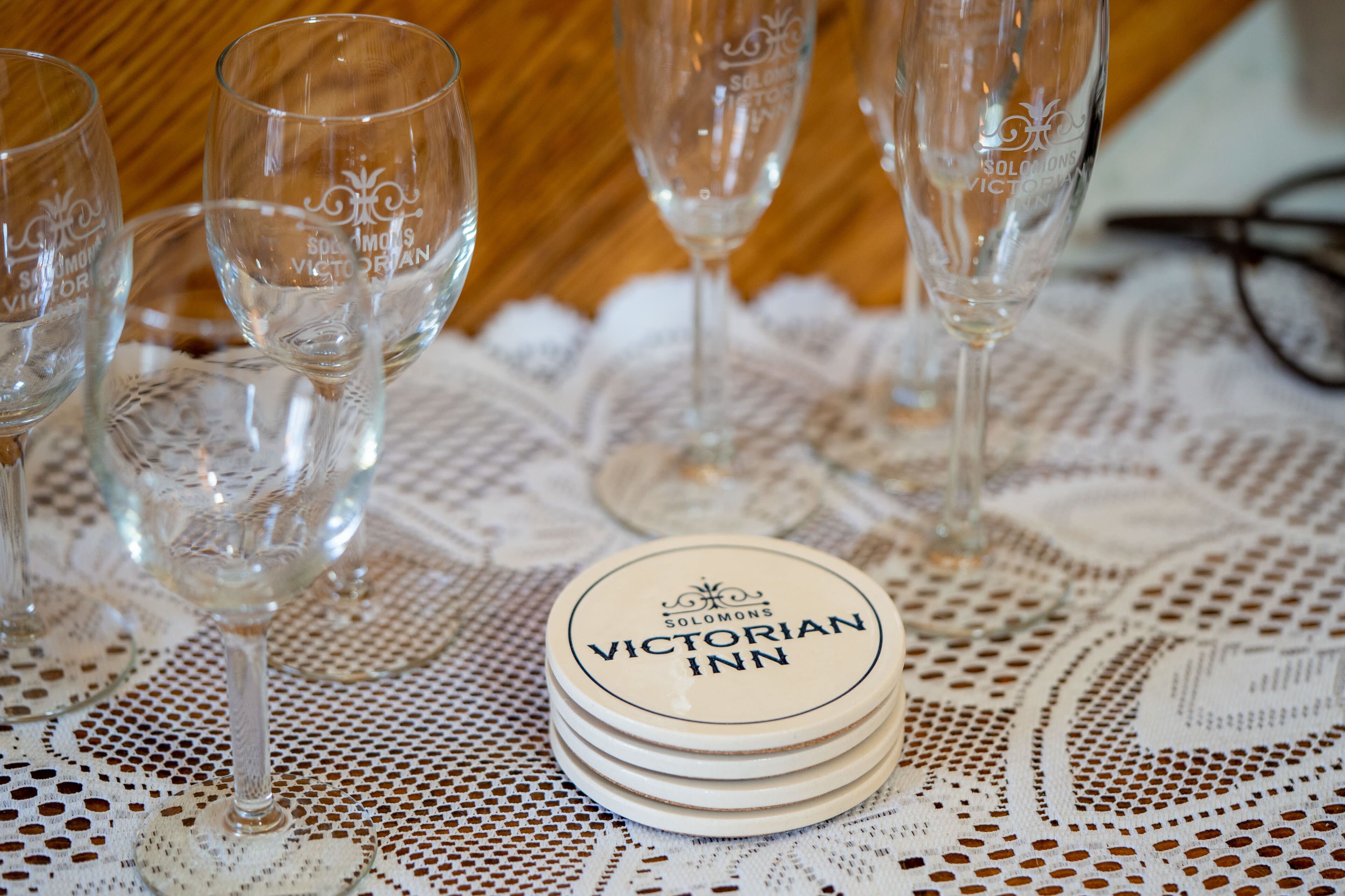 A stack of coasters with "Victorian Inn" branding on a lace tablecloth.