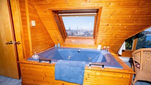Una cabaña de madera con hidromasaje, una ventana y una silla de mimbre.