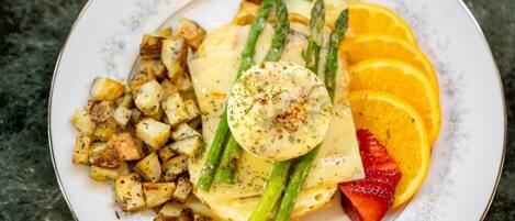 A plate of food with roasted potatoes, asparagus, orange slices, strawberries, and a poached egg.