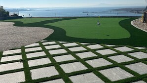 Een golfbaan met uitzicht op zee en verre bergen.