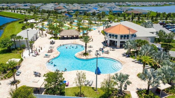 Un resort con una amplia piscina central, zona de playa y vistas del vecindario circundante.