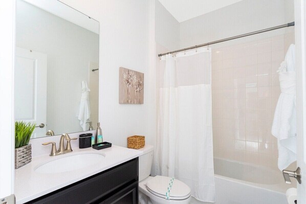 A modern bathroom with a white sink, a large mirror, a shower with a glass door, and a toilet.