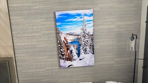 A cozy living room with a grey sofa, white and black throw pillows, a framed winter landscape picture, and a small Christmas tree on a wooden coffee table. - Cozy & Pet friendly Studio at Monache Resort in Village (Mammoth Lakes)