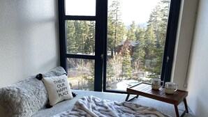 A cozy room with a large window, a plush sofa, a throw blanket, and a small table with cups. - Cozy & Pet friendly Studio at Monache Resort in Village (Mammoth Lakes)
