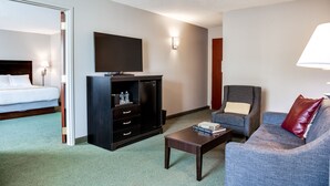 A hotel room with a bed, a television, a desk, a chair, and a sofa. - Hotel One75 (Hamilton)