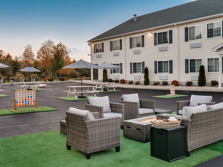 A spacious outdoor seating area with wicker furniture and umbrellas, a board game, and a building in the background.