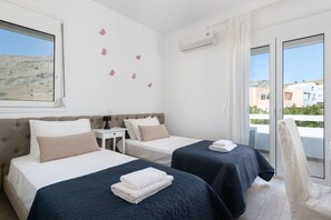 Ein Hotelzimmer mit zwei Betten, einem kleinen Tisch und Blick auf die Landschaft.