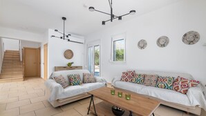 Una sala de estar moderna con dos sofás, una mesa de centro de madera y una escalera que lleva a otra habitación.