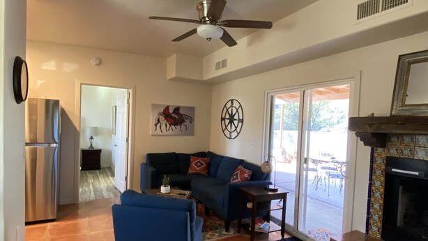 A spacious living room with a ceiling fan, a fireplace, and a large window.
