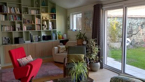 A living room with a sofa, armchairs, a coffee table, a bookshelf, and a large window with a view of the outdoors. - House (AYTRE)