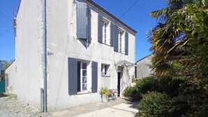 A two-story building with a gravel driveway and a small garden area. - House (AYTRE)