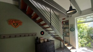A staircase with a wooden handrail and metal balusters, a black cabinet with books, a coat rack, and a wall-mounted emblem. - House (AYTRE)