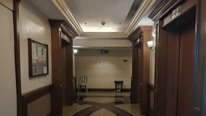 A hallway with a curved floor design, wooden doors, and a framed picture on the left wall.