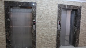 Two elevators with marble surrounds and digital floor indicators. - Magic Suite Mahboula-5 (Mahboula)