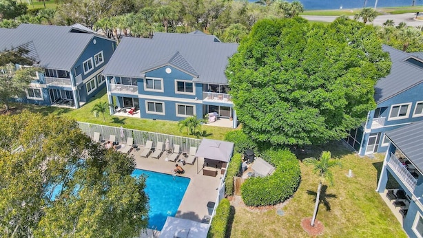 Un'ampia casa blu con piscina, immersa nel verde e affacciata su un lago.