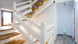 A staircase with wooden steps and white railings, leading to a room with a wooden floor and a door with a light switch. - Country house in Llanes for trips with family or friends  (Soberron, Llanes)
