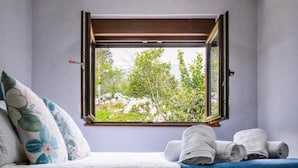 A bedroom with a bed, pillows, a window, and towels. - Country house in Llanes for trips with family or friends  (Soberron, Llanes)