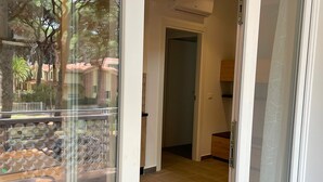 Ein Hotelzimmer mit Glastür zu einem Balkon, gefliestem Boden und sichtbarer Klimaanlage.