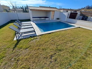 Une piscine dotée d’une terrasse carrelée et d’un espace salon abrité.
