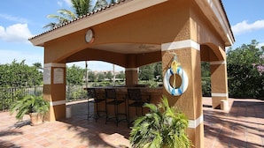 Une terrasse extérieure avec un coin bar, comprenant une horloge, des sièges et une bouée de sauvetage accrochée au mur.