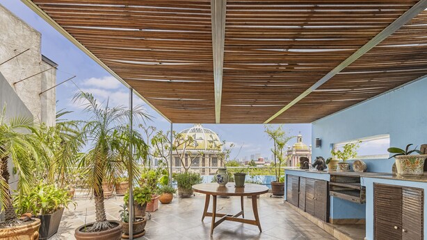 A rooftop terrace with potted plants, a wooden table, and a view of a cityscape with domed buildings. - Amazing PH w/great terrace in the heart of Condesa (Mexico)