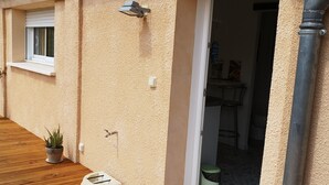 A building exterior with a wooden deck, a window, a wall-mounted light, and a door leading inside. - 1 Bedroom Apartment in Aubenas (Aubenas)