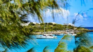 Un paisaje costero con barcos, una costa rocosa y edificios al fondo.