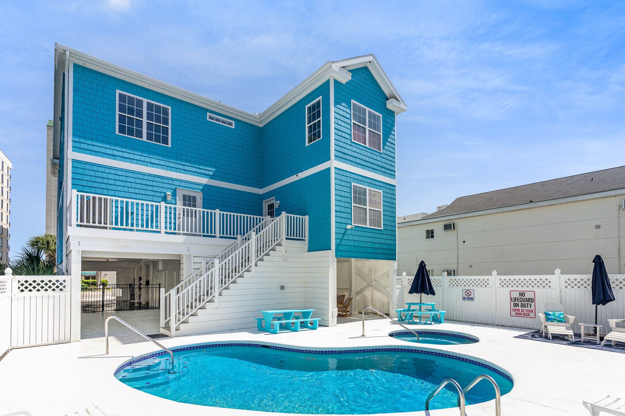 A two-story building with a pool area, including a staircase and outdoor seating.