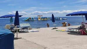 Une plage avec des parasols, des chaises longues et un toboggan aquatique.
