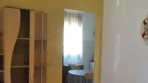 Une pièce avec une armoire en bois, une table à manger avec des chaises et un mur blanc orné d’un emblème circulaire.