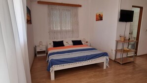 A bedroom with a bed, bedside table, lamp, and a television on a stand. - Apartments Vanja Škara Biograd - Studio Apartment with Terrace (Biograd na Moru)