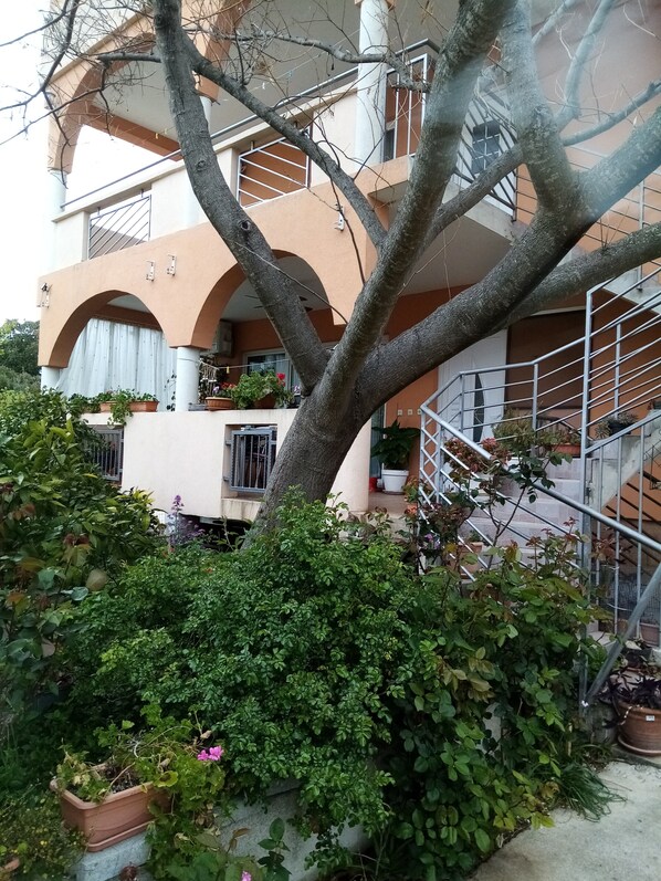 A multi-story building with balconies, potted plants, and a staircase.