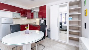 Una cocina moderna con armarios rojos, una mesa de comedor blanca y una estantería empotrada.